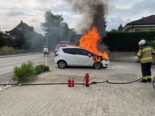 Feuerwehrkraft vor brennendem Auto