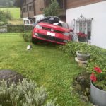 Vorderansicht roter VW Polo, der in einem Garten an der Hauswand steht