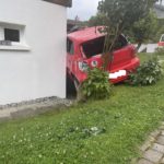 Rückansicht roter VW Polo, der in einem Garten an der Hauswand steht