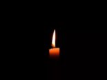 Symbolbild brennende Kerze im Dunkeln