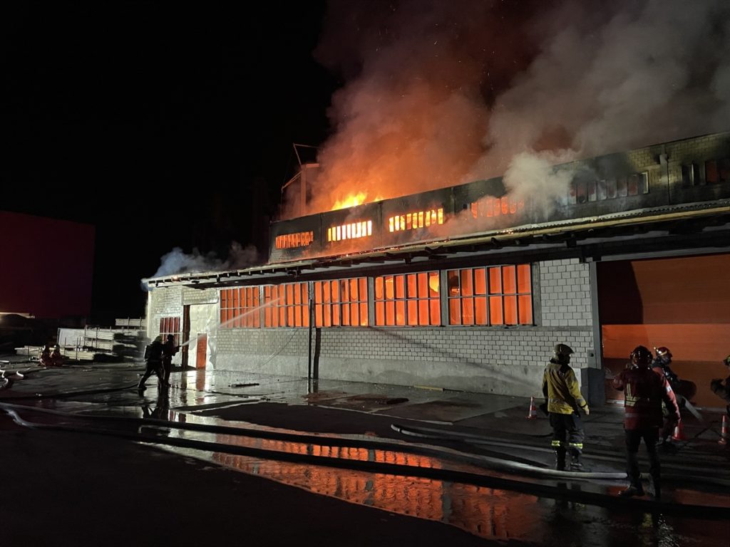 Lagerhalle in Vollbrand, davor Feuerwehrkräfte