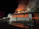 Lagerhalle in Vollbrand, davor Feuerwehrkräfte