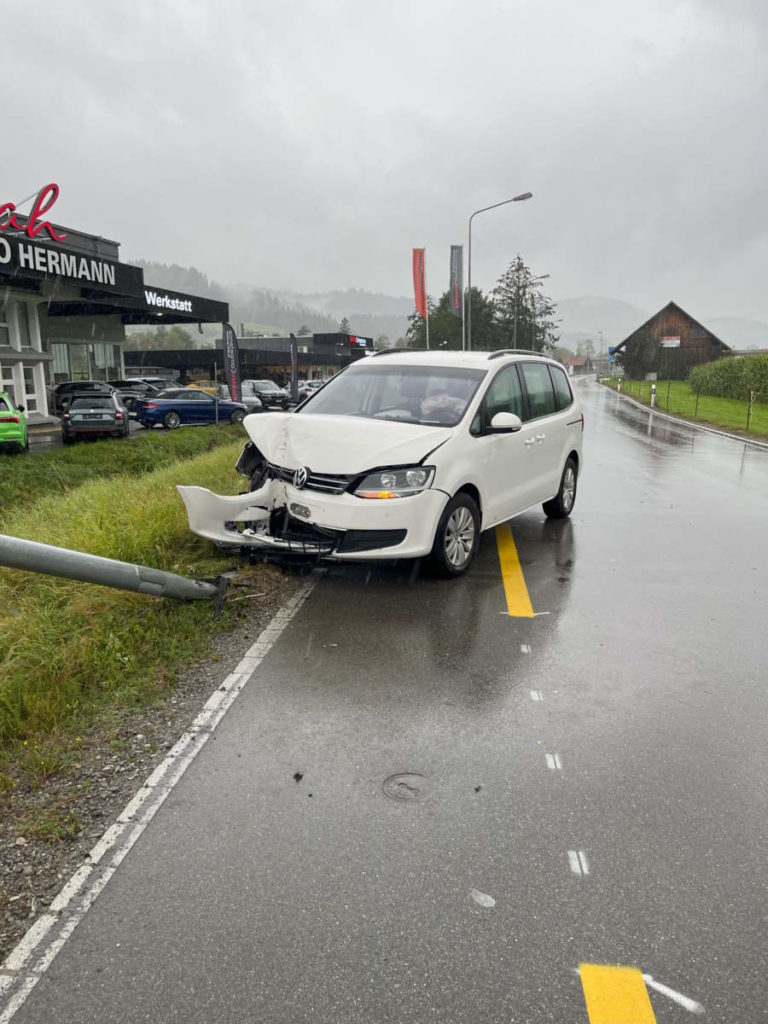 Demolierter weißer Wagen auf regennasser Fahrbahn