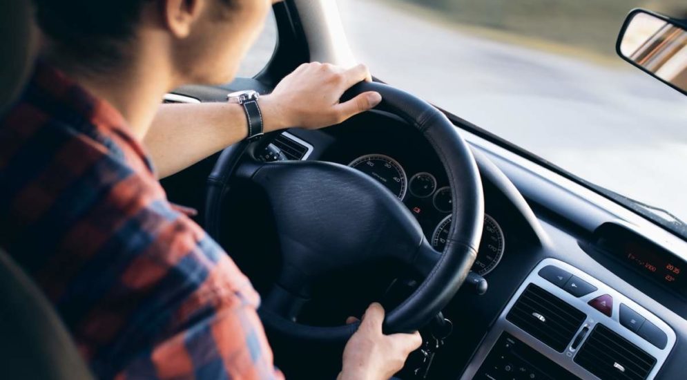 junger Mann sitzt am Lenkrad eines Autos