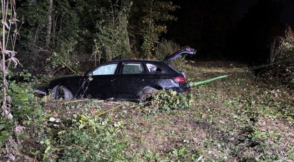 Unfallfoto: Schwarzer Audi steht mit geöffneter Heckklappe in der Böschung