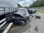 an der Front stark beschädigtes Auto neben Sattelschlepper, im Hintergrund ein weiteres Unfallauto