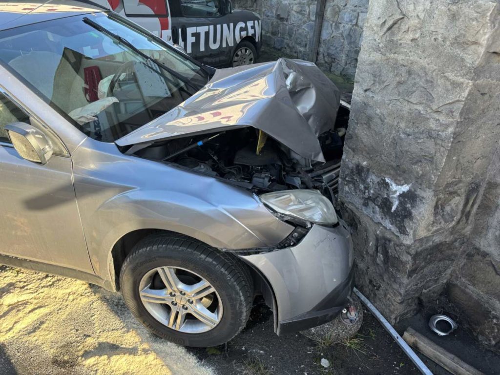 Auto mit zerstörter Motorhaube an Hauswand