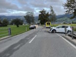 weisses Auto, dem beim Abbiegen auf die Strasse die Vorderfront beschädigt wurde. Auf der anderen Seite am Strassenrand das andere Unfallauto, im Hintergrund ein Rettungswagen.