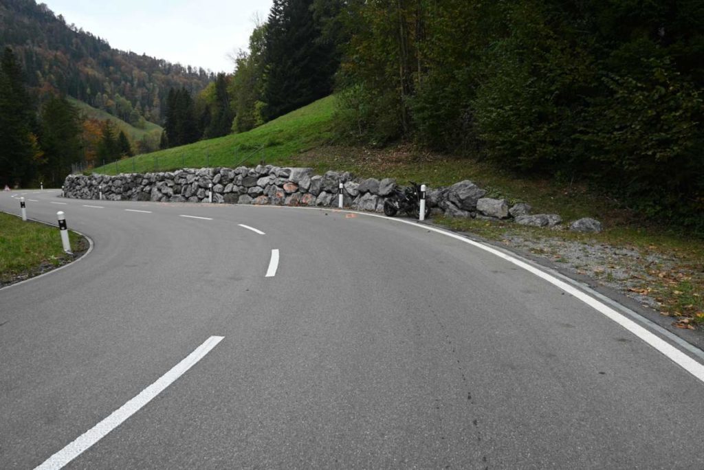 Schwarzes Motorrad steht in Kurve an Mauer