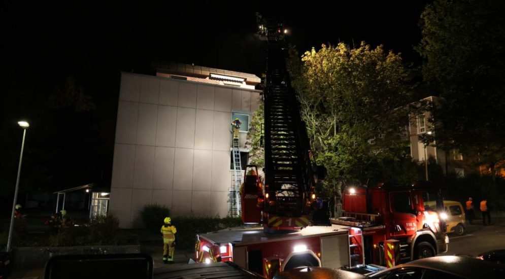 Mehrfamilienhaus im Dunkeln, davor ein Feuerwehrauto mit ausgefahrener Rettungsleiter