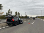 Schwarzes Unfallauto steht mit geöffnetem Kofferraumdeckel auf der Autobahn