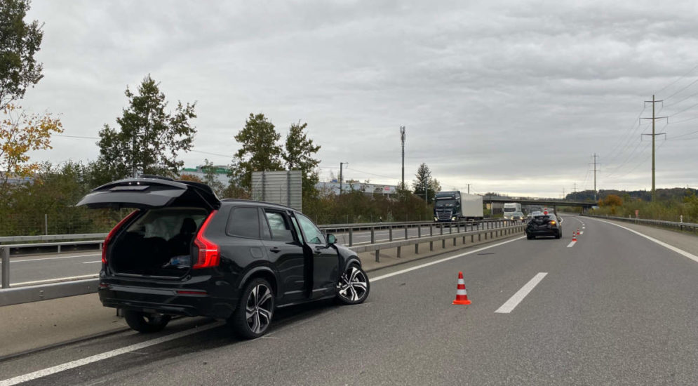 Schwarzes Unfallauto steht mit geöffnetem Kofferraumdeckel auf der Autobahn