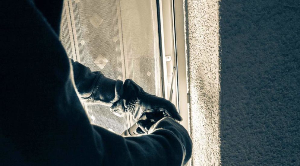 Symbolbild Einbruch: Schwarz behandschuhte Hände machen sich an Fensterrahmen oder Balkontür zu schaffen