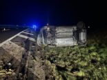 Auf dem Kopf liegendes Auto am Strassenrand bei Nacht