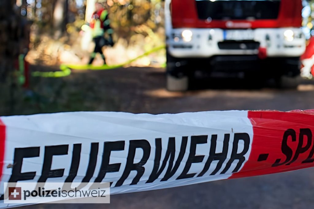 Symbolbild: Feuerwehrauto im Hintergrund, unten ein Feuerwehr-Sperrzonenband