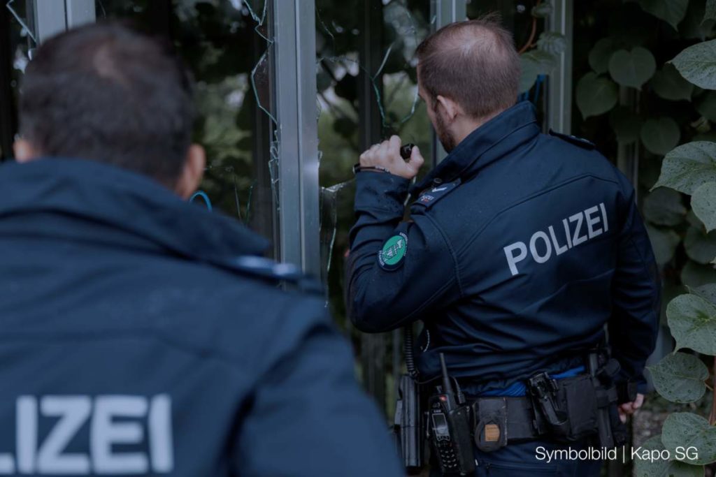 Symbolbild: Polizeibeamte leuchten durch zerbrochene Fensterscheiben