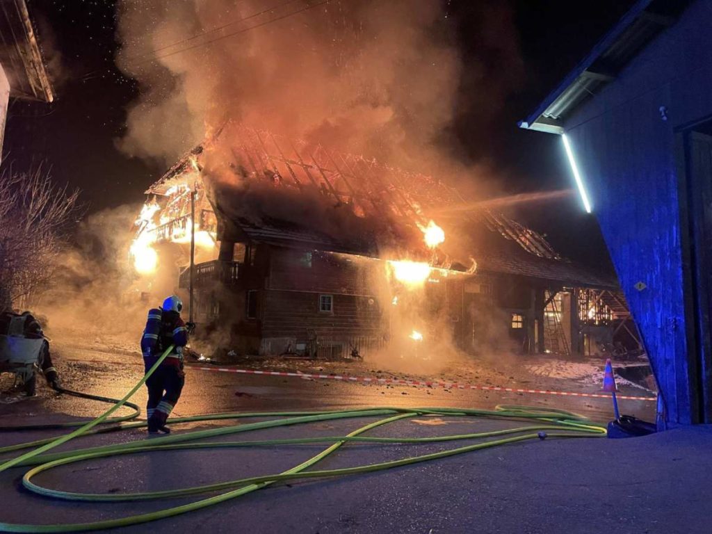 Feuerwehrkraft vor in Vollbrand stehendem Wohnhaus