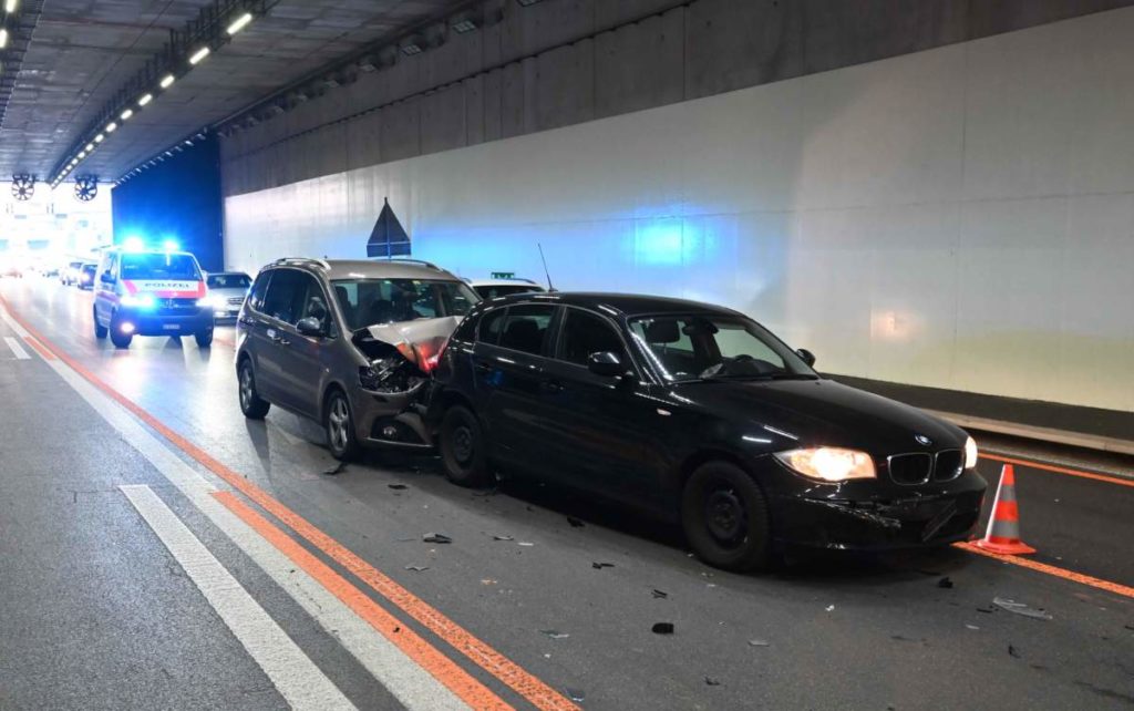 Unfallfoto: schwarzer BMW im Tunnel, dahinter ein graues Auto mit eingedellter Motorhaube